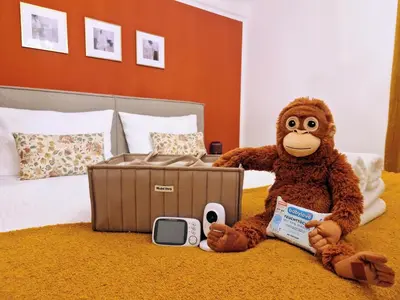 a stuffed monkey sitting on a bed with a suitcase at FEWOCASA Central Family Apartment Rorschach - Lake Constance - 15 min OLMA in Rorschach