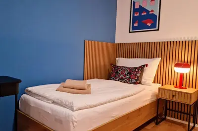a small bedroom with a bed with a red lamp at FEWOCASA Central Family Apartment Rorschach - Lake Constance - 15 min OLMA in Rorschach