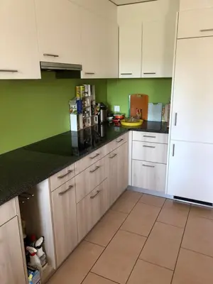 a kitchen with white cabinets and green walls at Appenzellerland Schöne Wohnung in einem Wandergebiet in Teufen