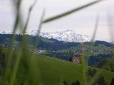 a house on a green hill with mountains in the background at Holiday Home Ferienhaus- - Stöckli Klingenbuch 20 by Interhome in Rehetobel
