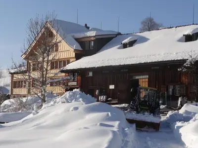 a house covered in snow with a tractor in front at Apartment Hof Bommes by Interhome in Gais