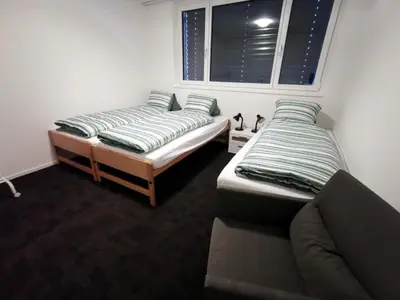 two beds in a room with a couch and a window at Apartment HIRSCHEN by Interhome in Gossau