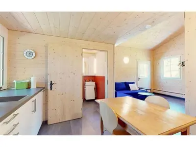 a kitchen and living room with a table and a blue couch at Apartment Vordere Au by Interhome in Schwellbrunn