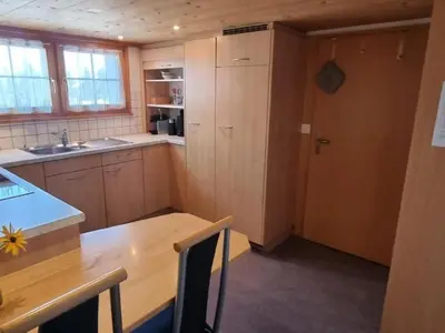 a kitchen with a wooden table and a counter top at Apartment Tiererlebnishof Windegg by Interhome in Urnäsch