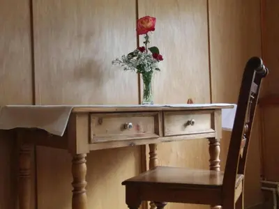a vase of flowers on a table with a chair at Holiday Home Frohheim by Interhome in Sankt Peterzell