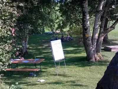 a sign in the grass with people sitting in the park at Holiday Home Frohheim by Interhome in Sankt Peterzell