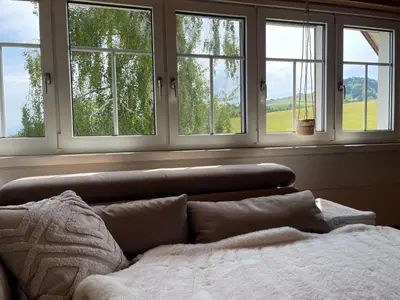 a bedroom with four windows and a couch with a bed at Apartment Wartheim by Interhome in Heiden
