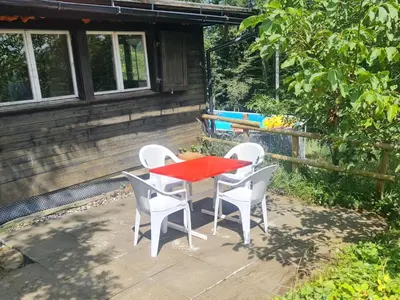 a red table and four white chairs on a patio at Holiday Home Bienenhaus Speicher by Interhome in Speicher