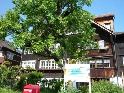 a tree in front of a building with a red phone booth at Holiday Home Appenzell House by Interhome in Thal