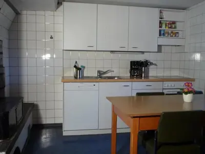 a kitchen with white cabinets and a wooden table at Holiday Home Appenzell House by Interhome in Thal