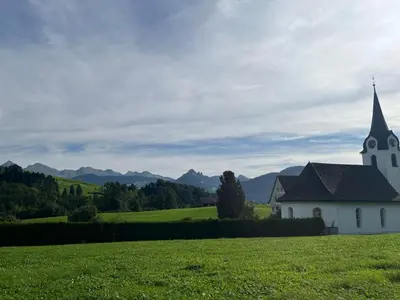 a church in a field with mountains in the background at Apartment Panoramablick by Interhome in Nesslau