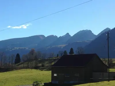 a barn in a field with mountains in the background at Holiday Home Seuzach by Interhome in Nesslau