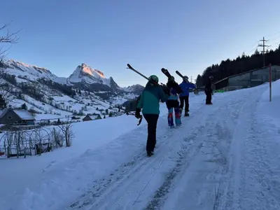 a group of people walking down a snow covered road with skis at Apartment Modern kompakt Speer by Interhome in Alt Sankt Johann
