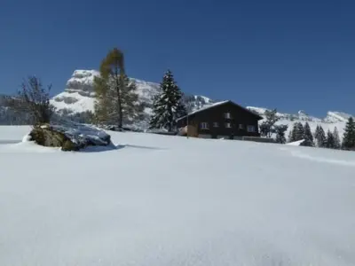 a snow covered hill with a house in the background at Holiday Home Oberguet by Interhome in Unterwasser