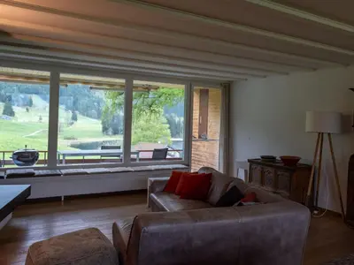 a living room with a couch and a large window at Holiday Home Haus am Schwendisee by Interhome in Wildhaus