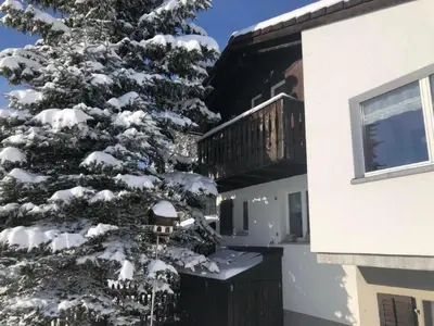 a snow covered pine tree in front of a house at Holiday Home Höckli by Interhome in Wildhaus