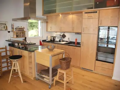 a kitchen with wooden cabinets and a island with a table at Holiday Home Befang 17 by Interhome in Wildhaus