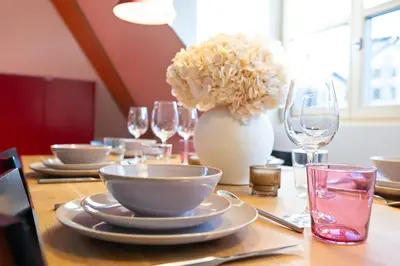 a table with plates and a vase with flowers on it at BLIV Exklusive Dachgeschosswohnung im Zentrum in St. Gallen