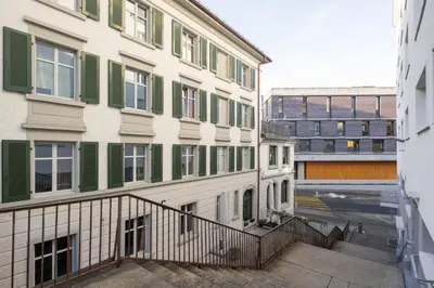 a building with green shuttered windows and a staircase at BLIV Exklusive Dachgeschosswohnung im Zentrum in St. Gallen