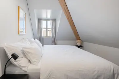 a white bed in a room with a window at BLIV Exklusive Dachgeschosswohnung im Zentrum in St. Gallen