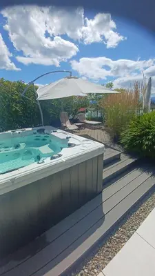 a large hot tub on a deck with an umbrella at Comfort Rooms mit Whirlpoolzugang in Romanshorn
