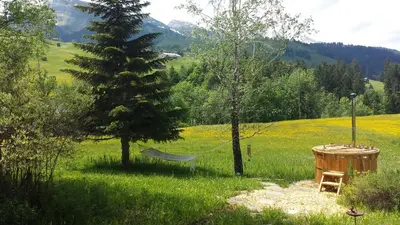 a chair and a table in a field with mountains at Chalet Chic mit Hot Pot in Wildhaus