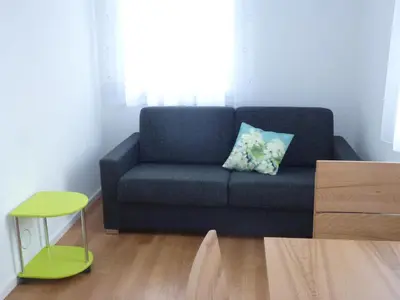 a living room with a blue couch and a green stool at Hotel Enjoy in Goldach