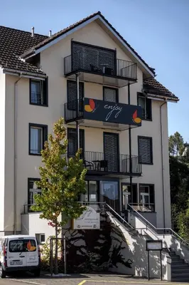 a white car parked in front of a building at Hotel Enjoy in Goldach