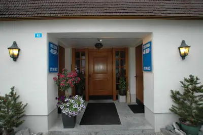 a front door of a house with flowers and plants at Hotel Pension Im Dorf in Zuzwil