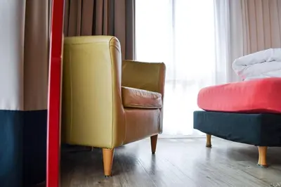 a living room with a yellow chair and a red chair at Hotel Landhaus Säntis Herisau in Herisau