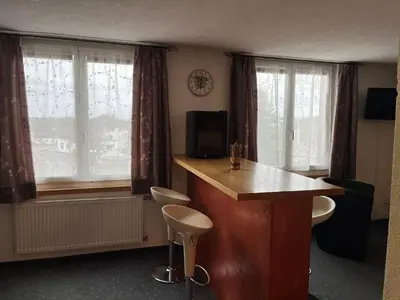 a kitchen with a counter and two windows with curtains at Hotel Bären Amriswil in Amriswil
