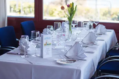 a table with wine glasses and a vase with red flowers at Park - Hotel Inseli in Romanshorn