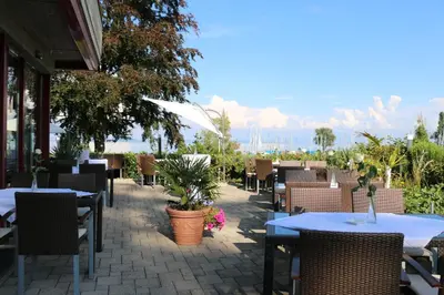 a white table with a vase of red flowers on it at Park - Hotel Inseli in Romanshorn