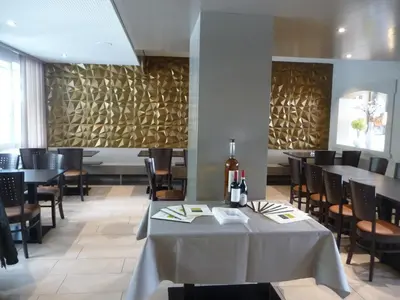 a dining room with tables and chairs and a wall at Hotel Bahnhof in Uzwil