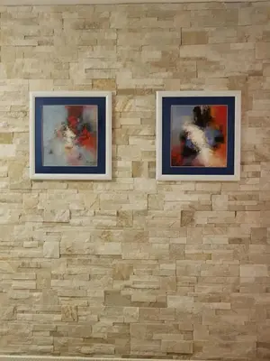 two framed paintings on a brick wall at Hotel Elite Self-Check-in in St. Gallen
