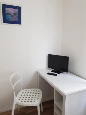 a white desk with a computer monitor and a chair at Hotel Elite Self-Check-in in St. Gallen