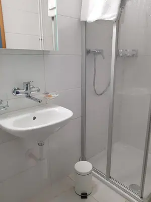 a white bathroom with a sink and a shower at Hotel Elite Self-Check-in in St. Gallen