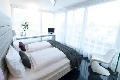 a white bedroom with a bed and a window at Sky Design Motel in Kriessern