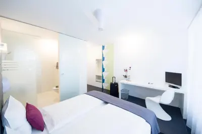 a bedroom with a bed and a desk and a sink at Sky Design Motel in Kriessern
