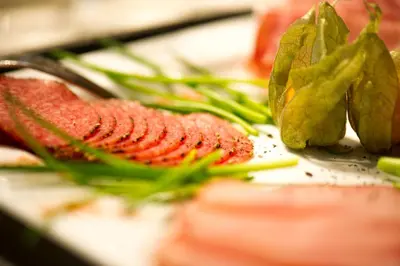a cutting board with meat and green vegetables on it at Sky Design Motel in Kriessern