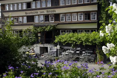 a building with tables and chairs in front of it at Gasthaus Rössli in Mogelsberg