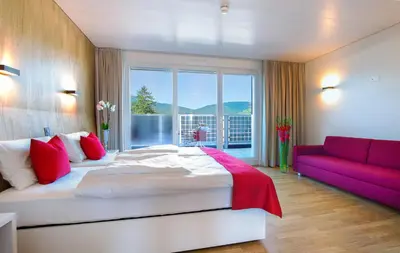 a bedroom with a large bed and a red couch at Hotel Restaurant Rhy in Oberriet