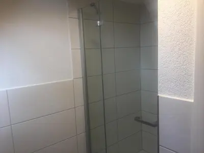 a shower with a glass door in a bathroom at Landgasthof Winzelnberg in Egnach