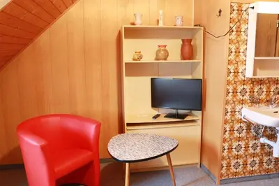a room with a red chair and a television at Restaurant Blume in St. Gallen