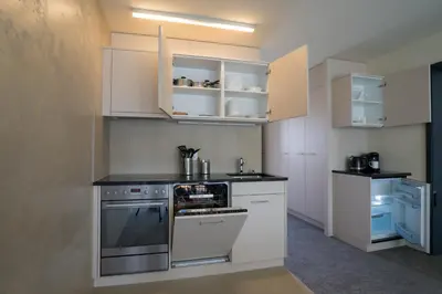 a kitchen with white cabinets and a stove top oven at wohnMOTEL - Hinterforst in Altstätten