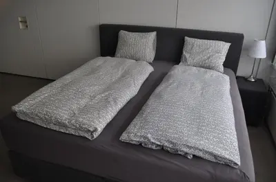 a bed with two sheets and pillows on it at Loft AR in Bühler