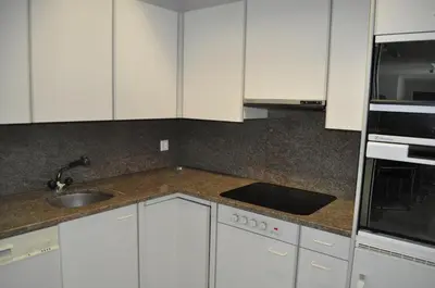 a kitchen with white cabinets and a sink at Loft AR in Bühler