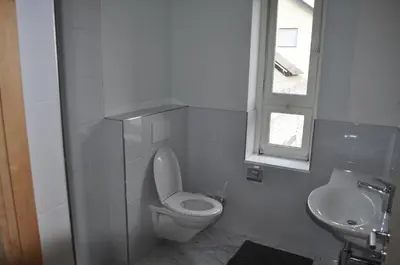 a white bathroom with a toilet and a sink at Loft AR in Bühler