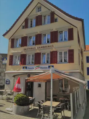 a building with tables and chairs in front of it at Pizzeria-Pension Gambrinus in Walzenhausen