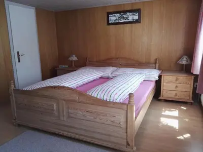 a bedroom with a large wooden bed and two night stands at Pizzeria-Pension Gambrinus in Walzenhausen